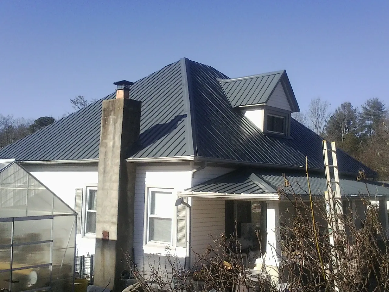 Dark blue standing seam metal roof on a white farmhouse with dormer — Slate & Tile Roof Repair by Roofing Brothers in Lanark