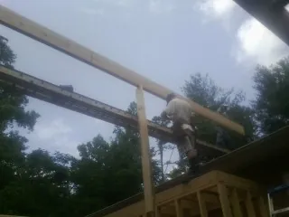 Carpenter setting a ridge beam over a new addition frame — Ice Dam Removal by Roofing Brothers in Lanark