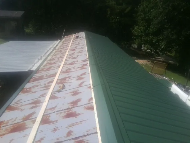 Old rusted panels beside newly installed green metal roofing — Wind Damage Roof Repair by Roofing Brothers in Lanark