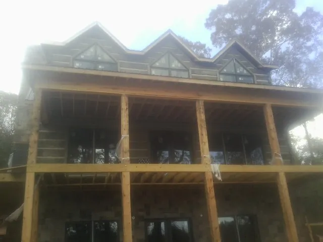 Dormers and porch framing on a large log home under construction — Roof Coating work by our crew in Lanark