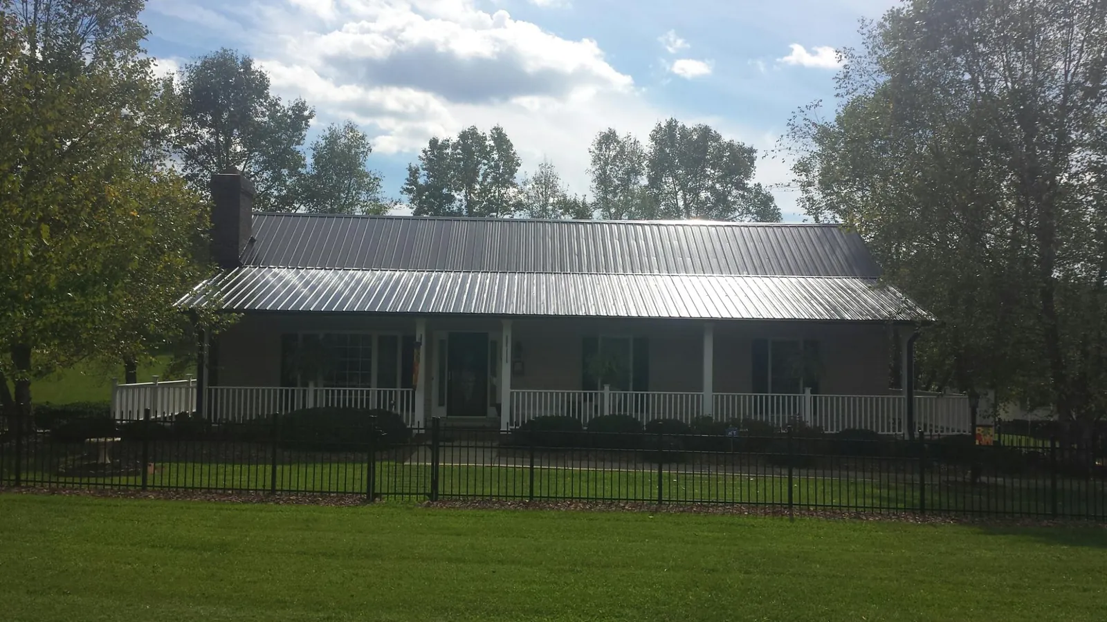 Gray metal roof on a brick ranch with a full width front porch — Gutter Guard Installation work by our crew in Lanark