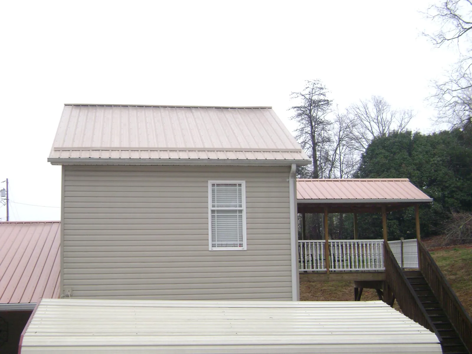 Tan metal roofs on a two story addition and attached porch, from a Roof Replacement job in Lanark