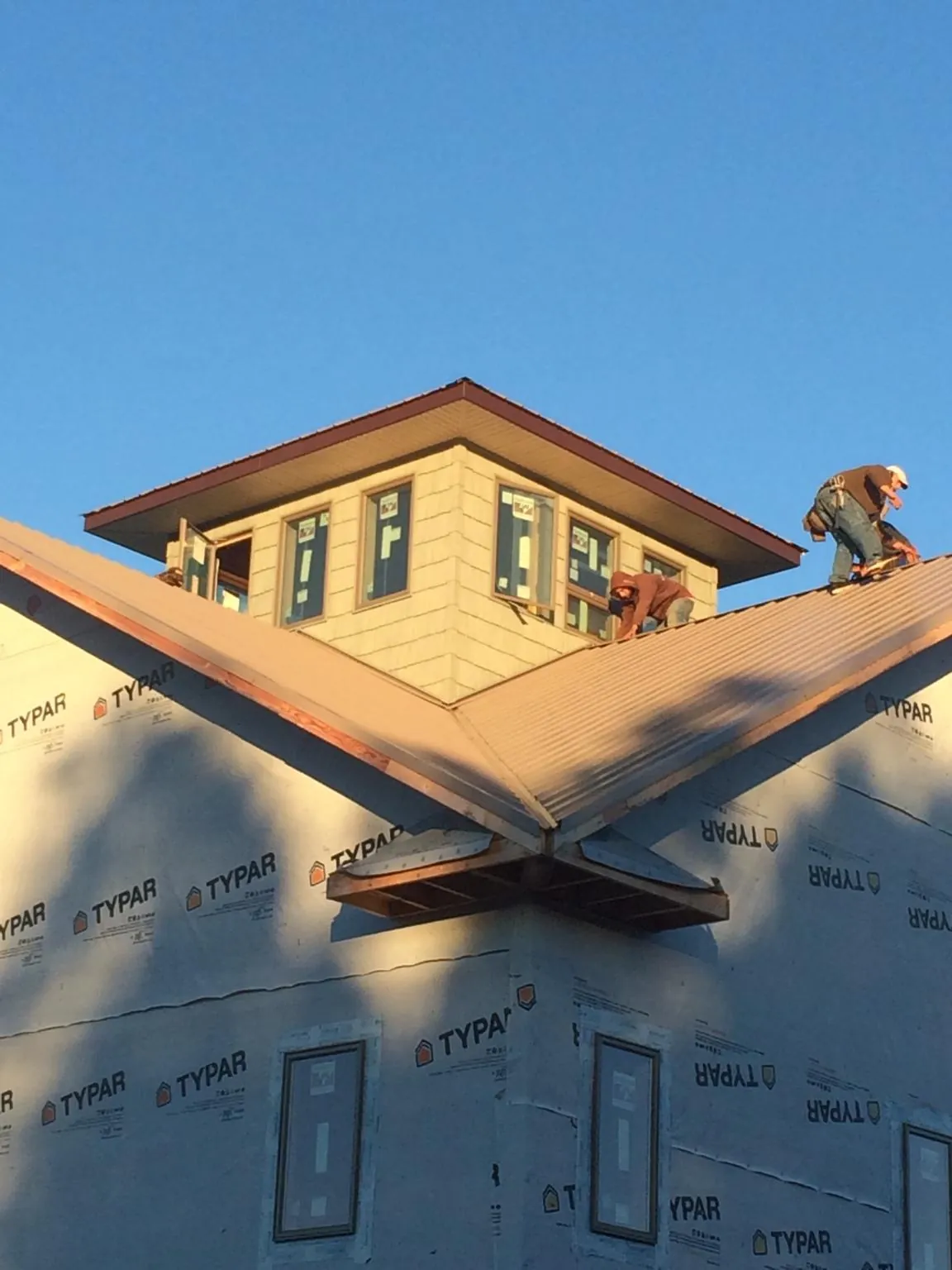 Roofers working around a rooftop cupola on a new metal roof at sunset — Roof Waterproofing in Lanark by Roofing Brothers